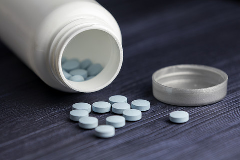 A white pill bottle on its side with scattered pills.