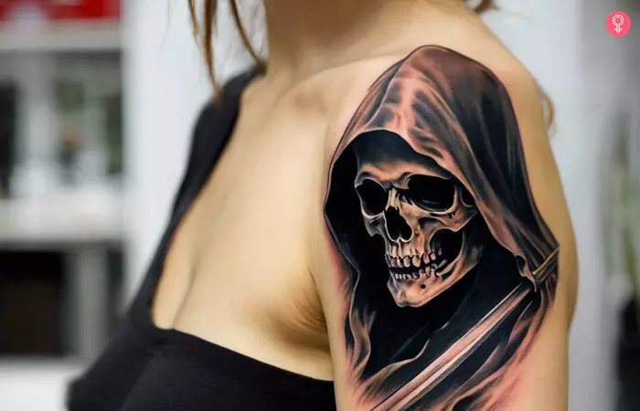 Realistic Grim Reaper tattoo on a woman’s upper arm, showcasing chilling realism with subtle black, grey, and pink shading, highlighting the skull and scythe, evoking fear, fascination, and the fragility of life.