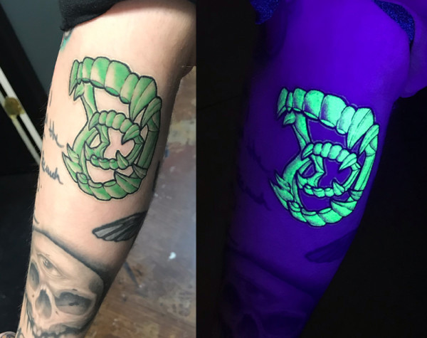 A Xenomorph teeth tattoo by Quinton McCloud, showcasing the vibrant glow of UV ink under black light.