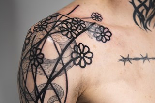 Detailed blast over tattoo, showing intricate blackwork design layered over an older, colorful tattoo.