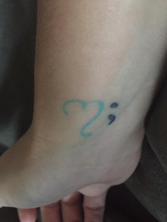 Tattoo of a semicolon paired with an open, incomplete heart, symbolizing loss and suicide awareness.