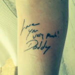 Tattoo of handwritten message "I love you very much! -Daddy" on a woman's arm.