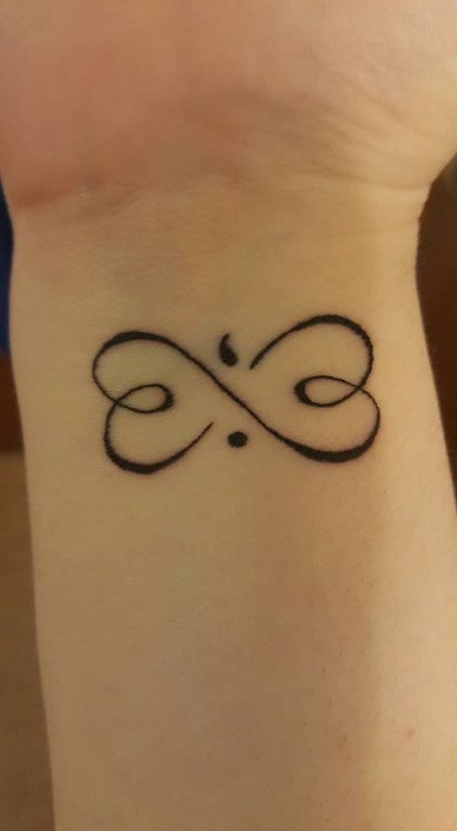 Wrist tattoo showing an infinity symbol intertwined with a semicolon in the center, representing hope and suicide awareness.