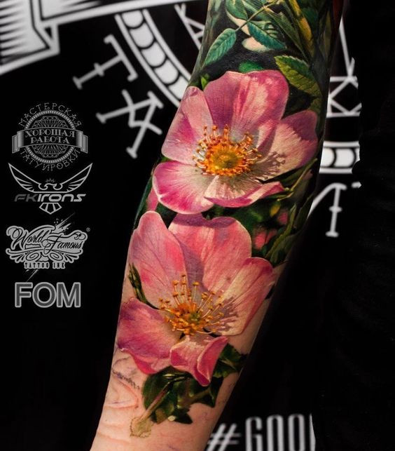 Close-up of a realistic pink flower tattoo on a forearm, created by World Famous Tattoo Ink artist.