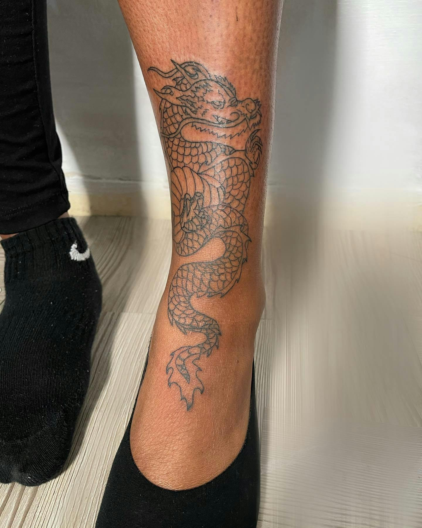 Bold dragon ankle tattoo for women