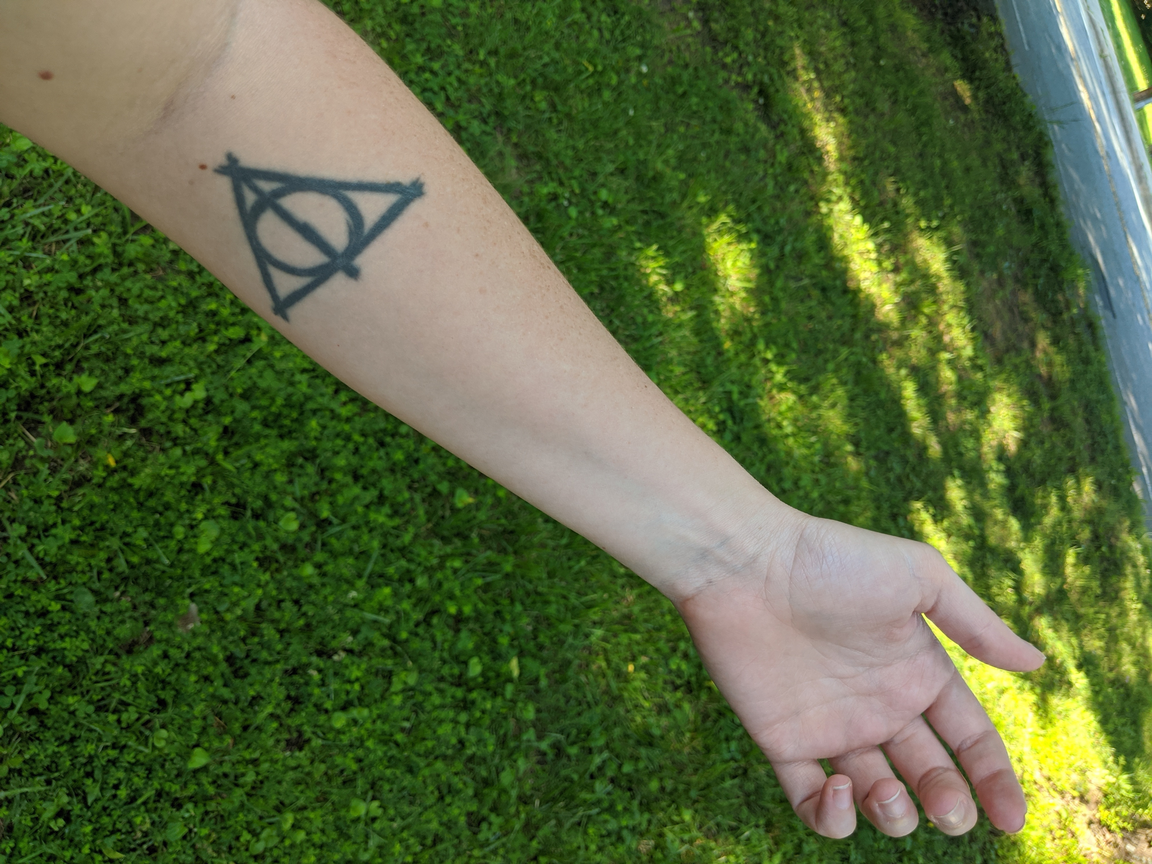 A tattoo of the deathly hallows on a forearm.