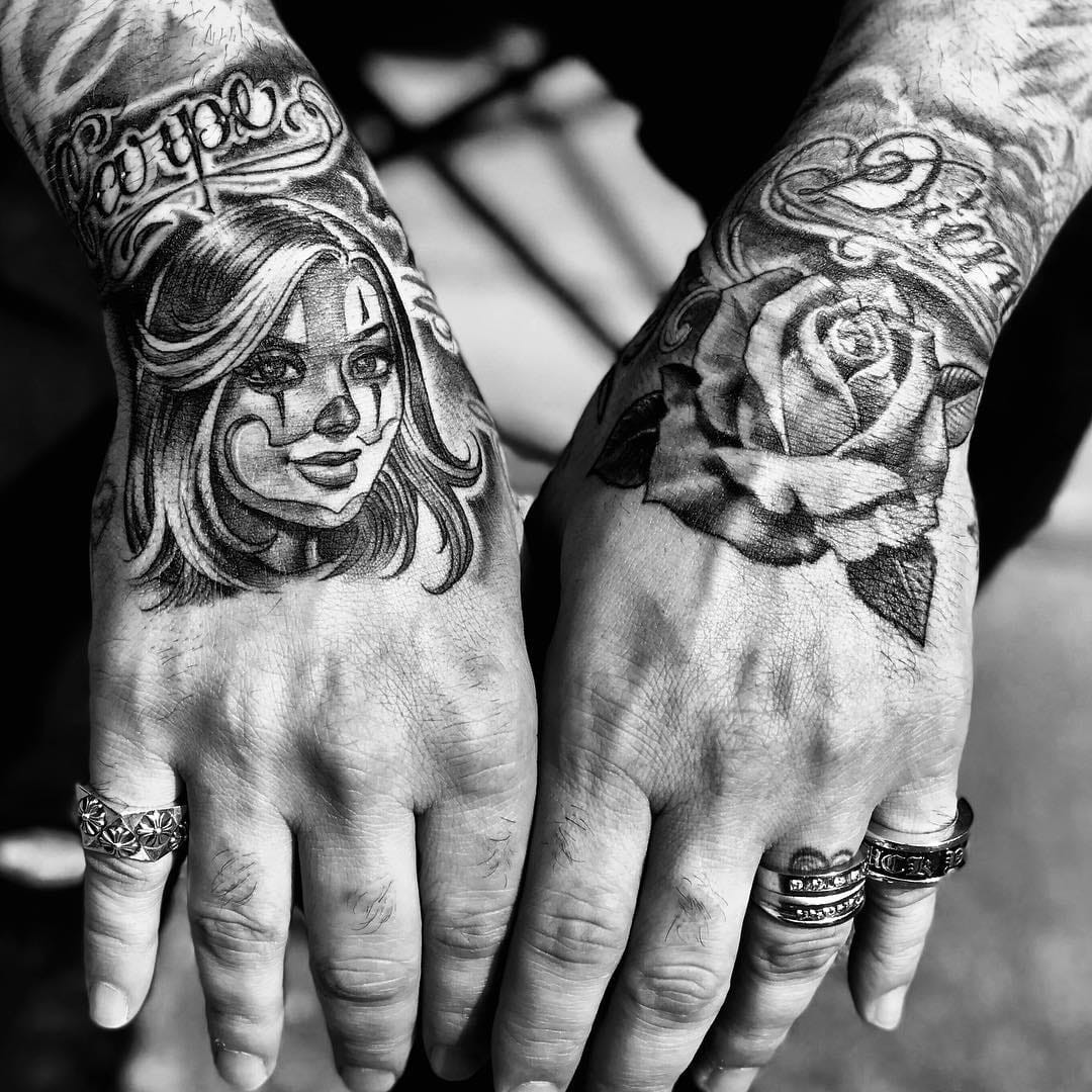 Tattoo by Mister Cartoon. Signature Chicano script tattoo by Mister Cartoon, incorporating roses and a payasa, rendered in black and grey, highlighting the fine line detail and iconic imagery associated with Mister Cartoon's Chicano tattoo style.