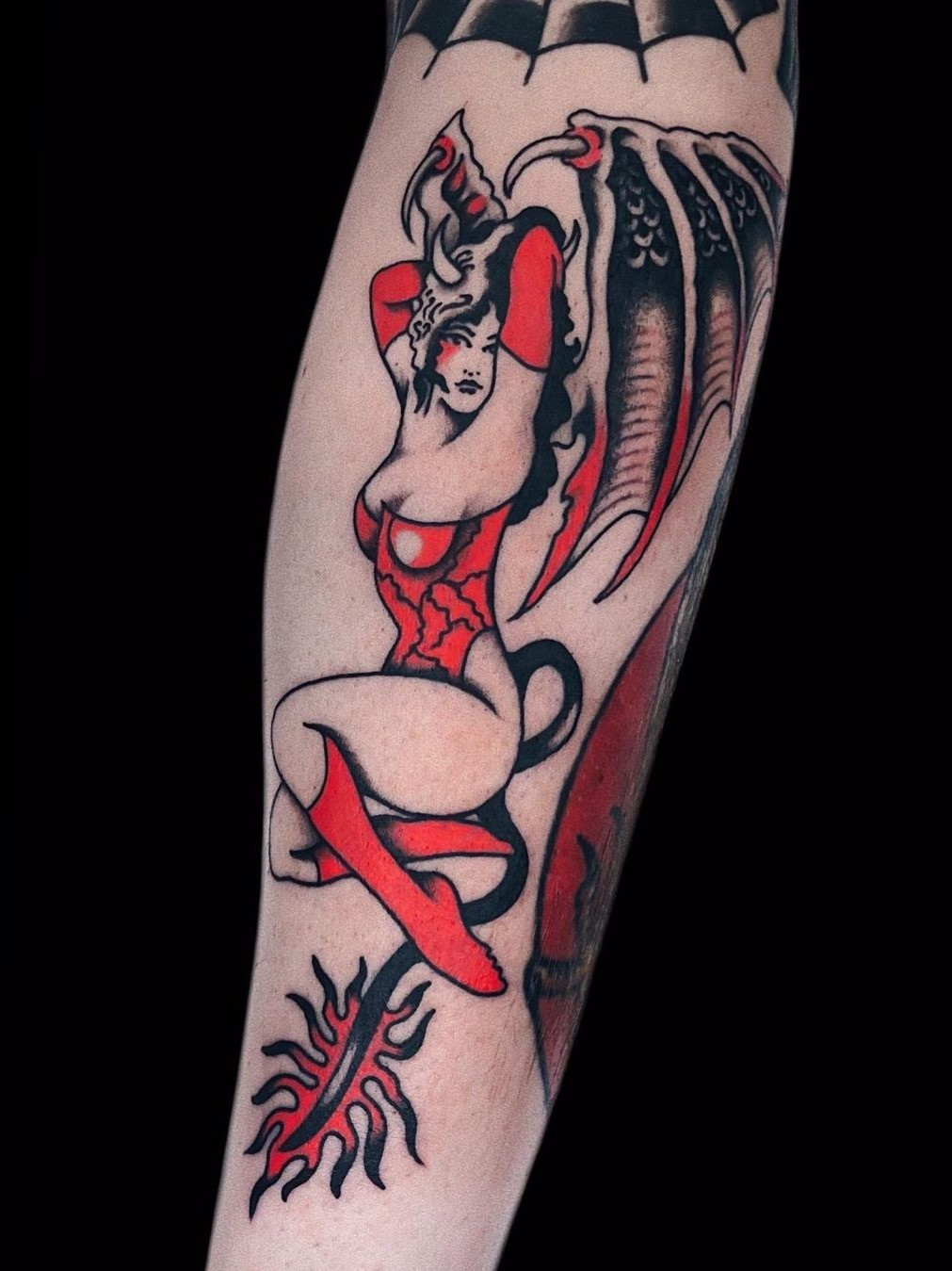 Classic Sailor Jerry female pin-up tattoo with bold lines and nautical symbols, showcasing the traditional style's origins.