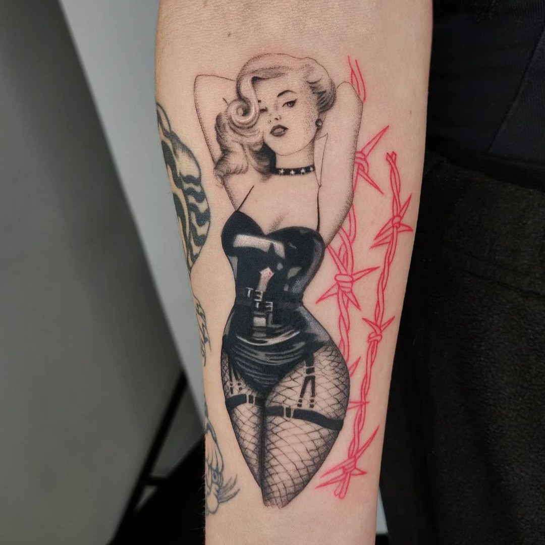 Sailor Jerry style female pin-up tattoo with bold outlines and nautical imagery.