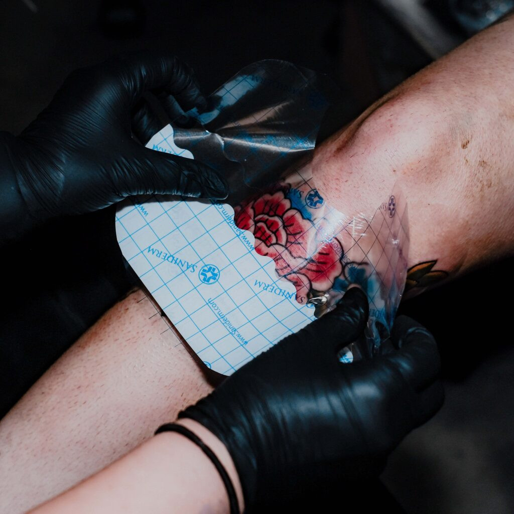 Close-up of a person cleaning a fresh tattoo with foam soap before applying Saniderm