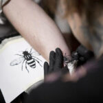 Worker bee tattoo on forearm in black ink, symbolizing Manchester's unity and resilience.