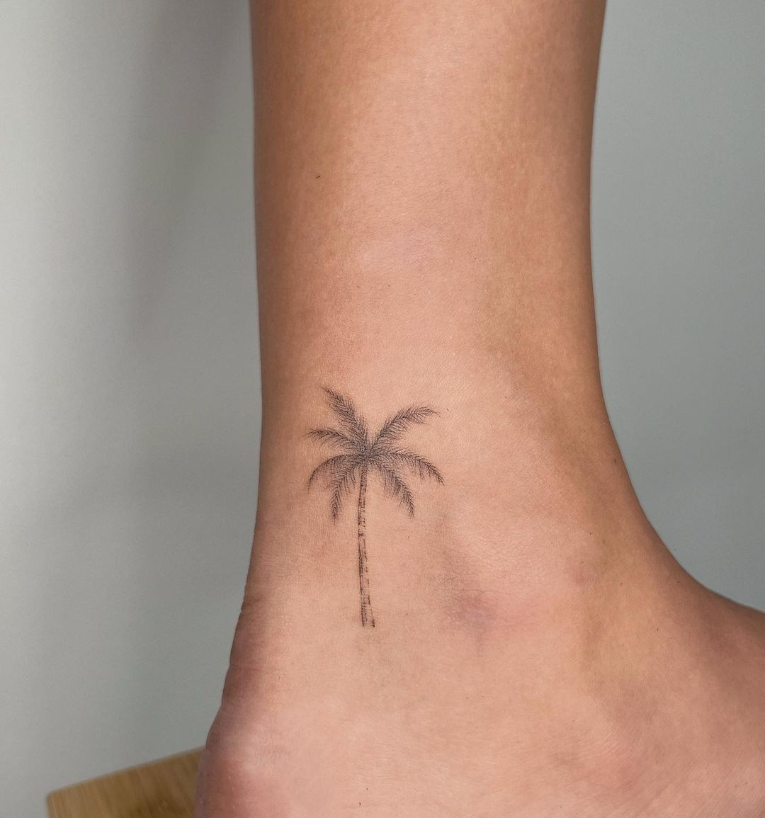 Palm tree tattoo on ankle, minimalist and beach-themed design