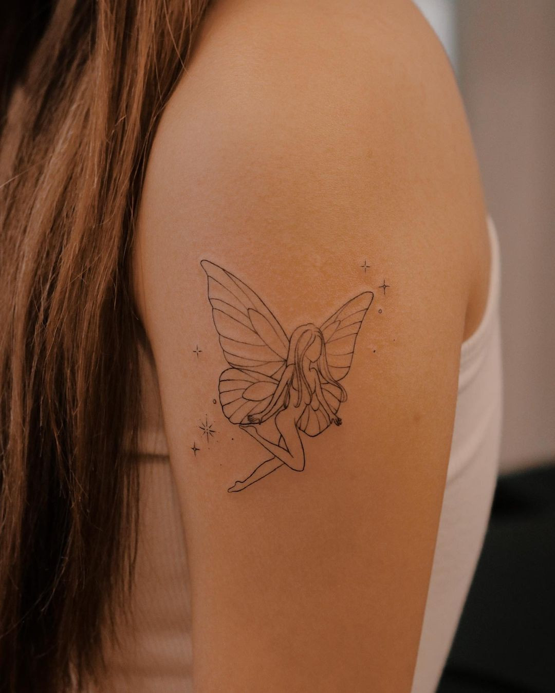 Fairy tattoo on back of arm, whimsical and star-detailed design