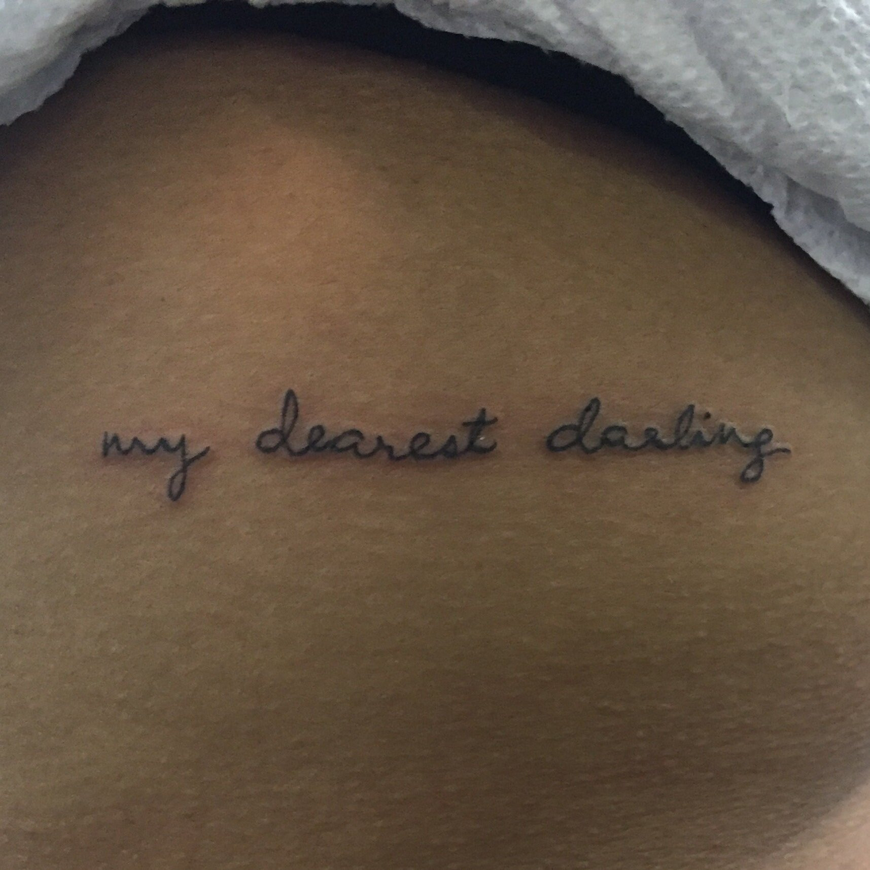 Close-up of Henah's side tattoo, the phrase &quot;my dearest darling&quot; in elegant cursive handwriting, a tribute to her mother's loving words.