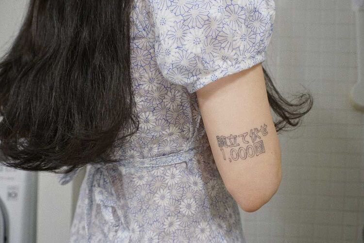 Close-up of Evania's arm tattoo, the Kanji characters for &quot;1,000 push-ups&quot;, representing a personal mantra of self-trust and reliance on support systems.