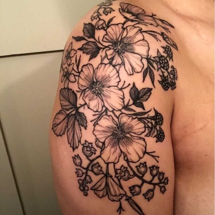 Close-up of Nat's shoulder tattoo, a floral arrangement featuring a California Poppy and Lily of the Valley, symbolizing her love and bond with her two step-daughters.