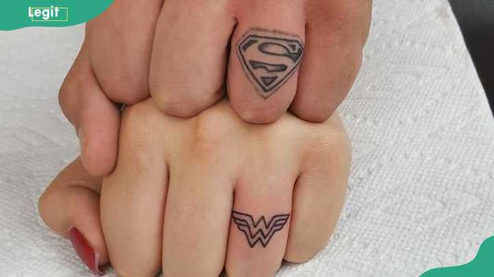 Superhero symbols ring tattoos for a bold and fun expression of a strong bond.