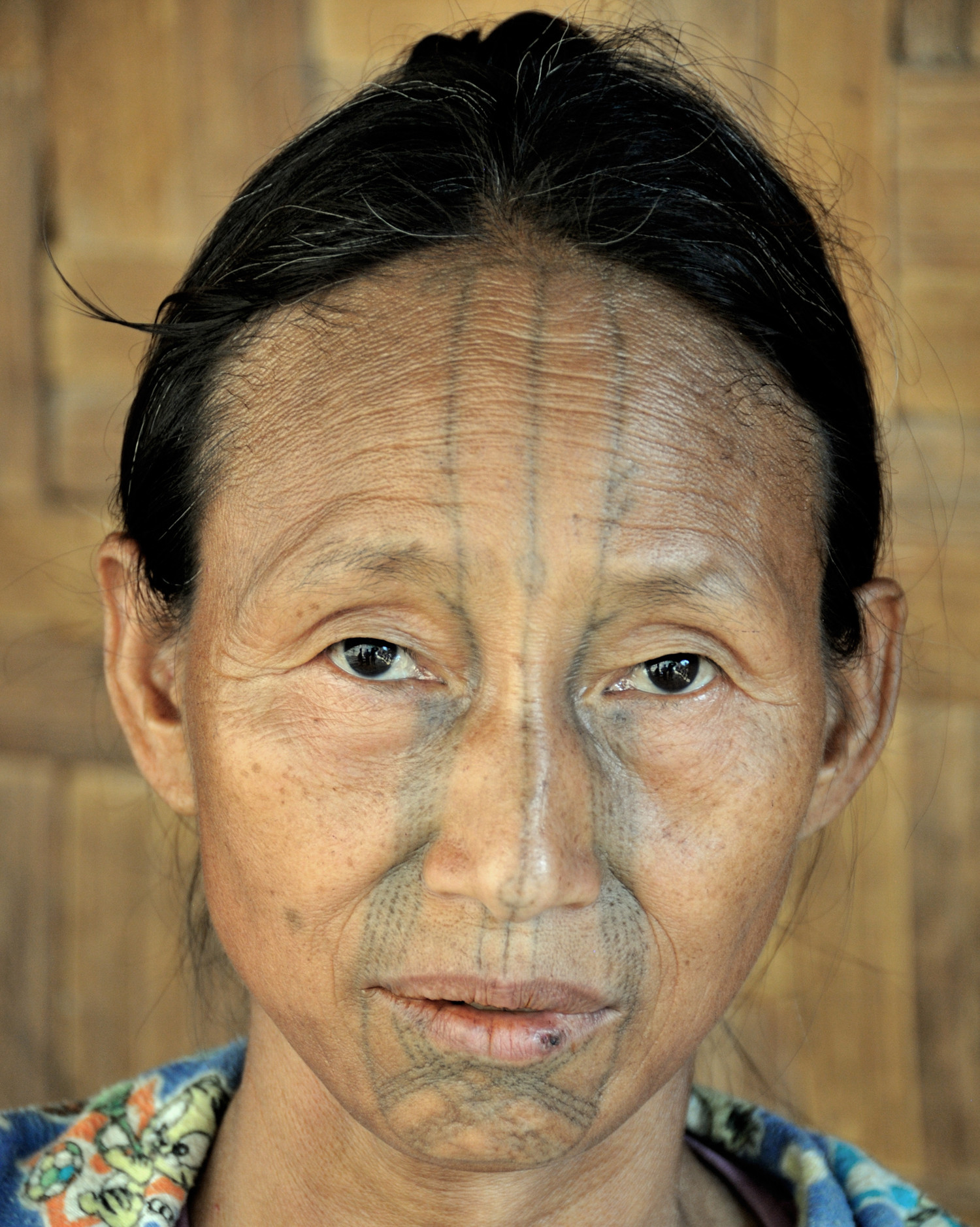 Ma Kakar, a Yonkon woman showcasing the distinctive &quot;tear&quot; tattoos extending from her eyes. These tattoos are believed to offer spiritual protection and ensure ancestral recognition.