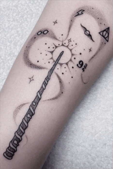 Monochromatic wand tattoo surrounded by wizarding world elements, a magical themed tattoo idea