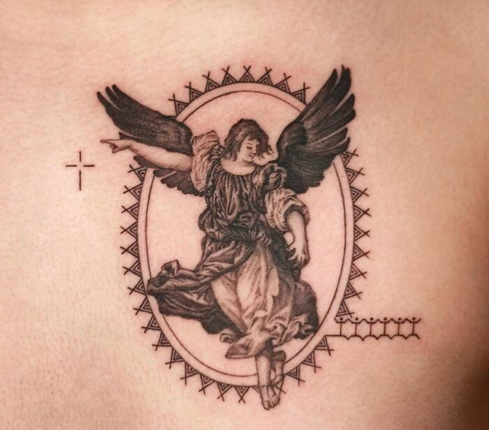 Gothic tattoo of an angel with wings, framed in an ornate oval design, conveying a sense of classic gothic artistry.