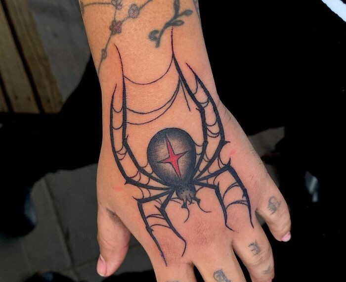 Hand gothic tattoo of a spider with web details, showcasing intricate gothic design elements and fine lines.