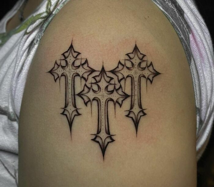 Gothic tattoo featuring three ornate crosses in black ink on an arm, showcasing detailed gothic cross designs.