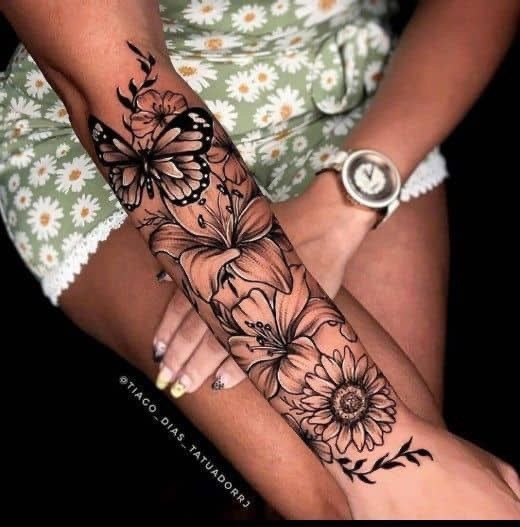 Floral and butterfly forearm tattoo on a woman wearing a green daisy-patterned dress and silver watch.