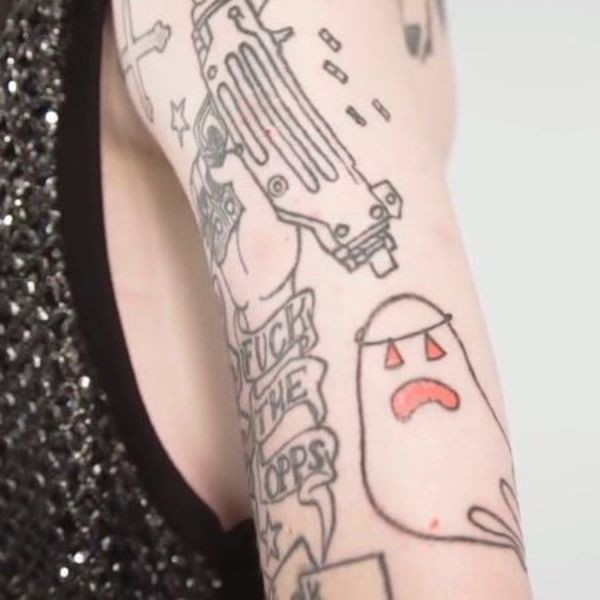 Lil Peep's bicep and arm tattoos featuring &quot;Fuck the Cops&quot;, a gun hand, and a Halloween ghost.