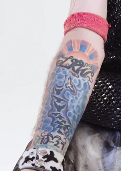 Lil Peep's forearm tattoo featuring birds and clouds.