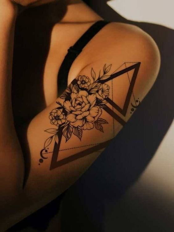 Floral and geometric arm tattoo with black ink, showcasing intricate flower and triangle design. Modern, elegant body art.