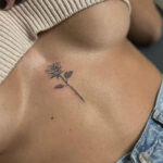 Minimalist rose tattoo under bust on woman