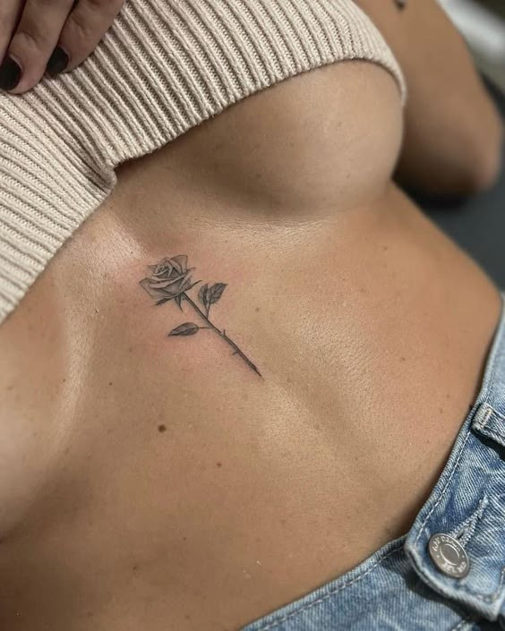 Minimalist rose tattoo under bust on woman