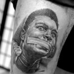 Close-up shot of a tattoo artist working on a detailed black and gray realism tattoo, showcasing expertise and focus.