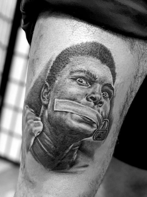 Close-up shot of a tattoo artist working on a detailed black and gray realism tattoo, showcasing expertise and focus.