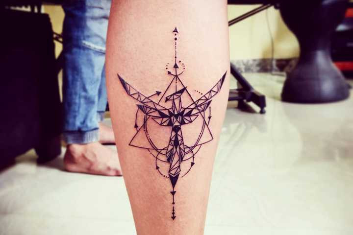 An artistic geometric phoenix tattoo on a woman's leg, incorporating lines and shapes to symbolize harmony, balance, and a modern interpretation of rebirth through body art.