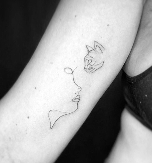 A single line abstract tattoo depicting a face alongside a cat's head, symbolizing the bond between owner and pet.