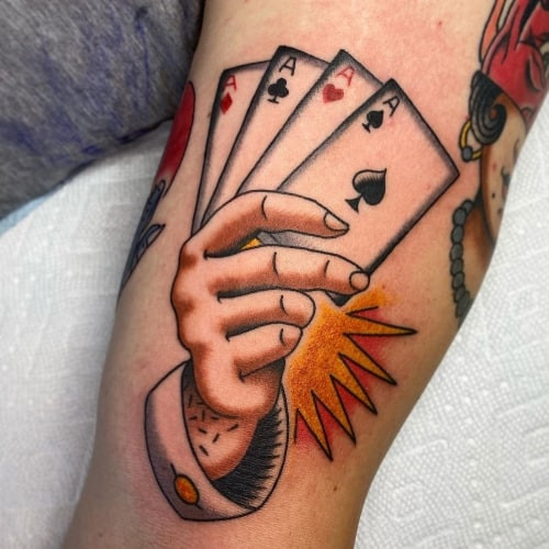 An Ace of Hearts tattoo with artistic details on a man's arm, representing winning hand