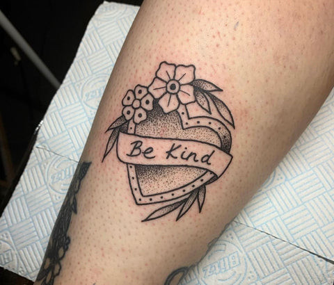 Two 'Be Kind' heart tattoos in different styles, one in black dot work and the other in bold color, by Becky Pope, showcasing adaptable designs for girly best friend tattoos.