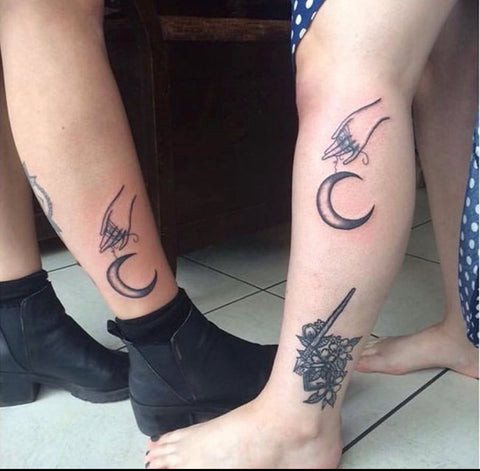 Matching moon tattoos held by hands, a symbol of deep friendship and connection, on Amber and Jess.