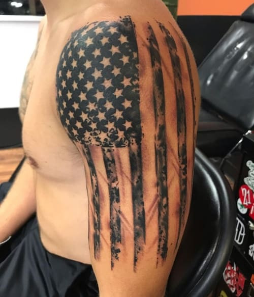 American flag waving tattoo on a man's shoulder