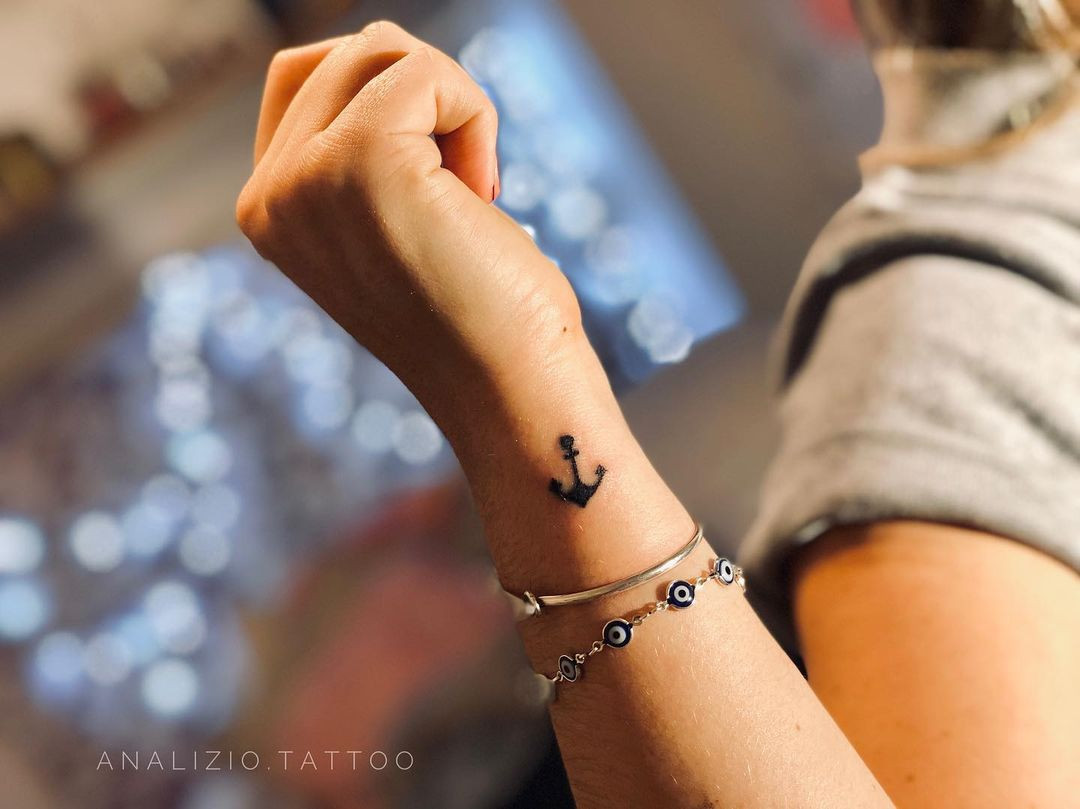 Anchor tattoo on wrist, minimalist and stability symbol