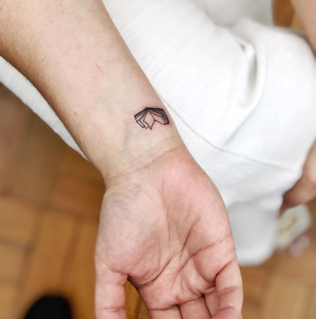 Minimalist book tattoo on wrist, simple lines and literary theme