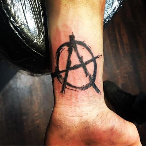 Small anarchy symbol tattoo on the finger, a subtle yet impactful men tattoo idea.