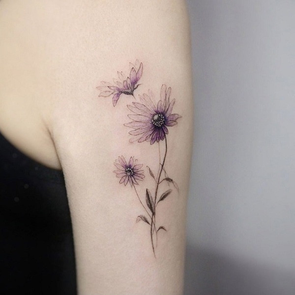 Realistic style aster flower tattoo in soft pastel colors, with detailed petals and leaves, on the shoulder.