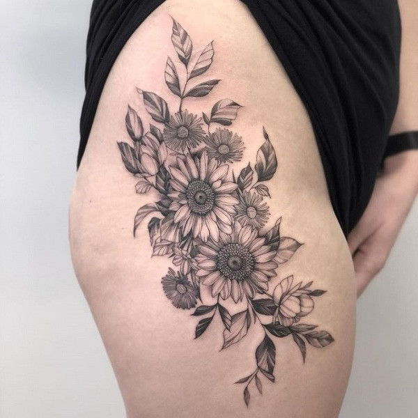 Negative space aster flower tattoo, using the skin as the flower shape, outlined in black ink, on the finger.