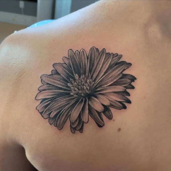 Geometric and floral hybrid aster flower tattoo, combining sharp geometric shapes with delicate petals, on the ribcage.