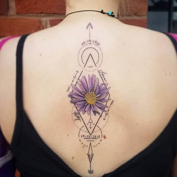 Shoulder blade aster flower tattoo in watercolor style, featuring soft blue and purple hues with green leaves.