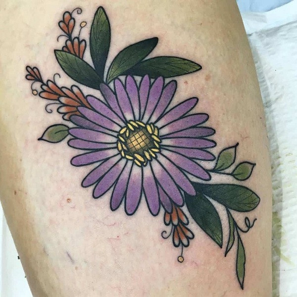 Ornamental aster flower tattoo with intricate patterns and decorative elements surrounding the flower, on the thigh.