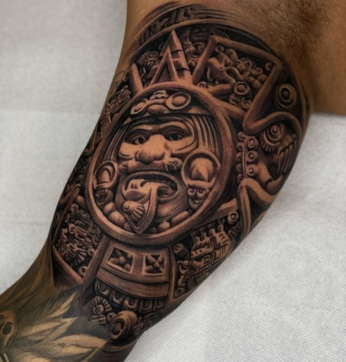 Two aztec tattoos on men, one on the forearm with a traditional Aztec warrior and another on the arm with an Aztec calendar design.