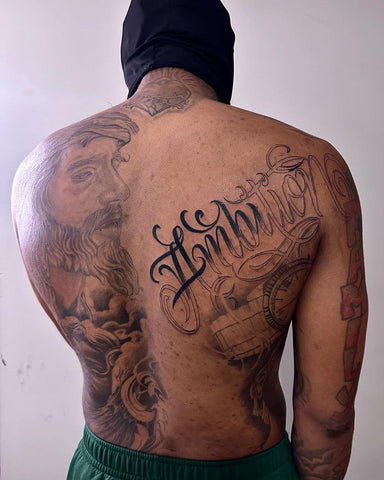 Personalized back tattoo names for men featuring a surname script across the upper back, signifying family and personal identity.